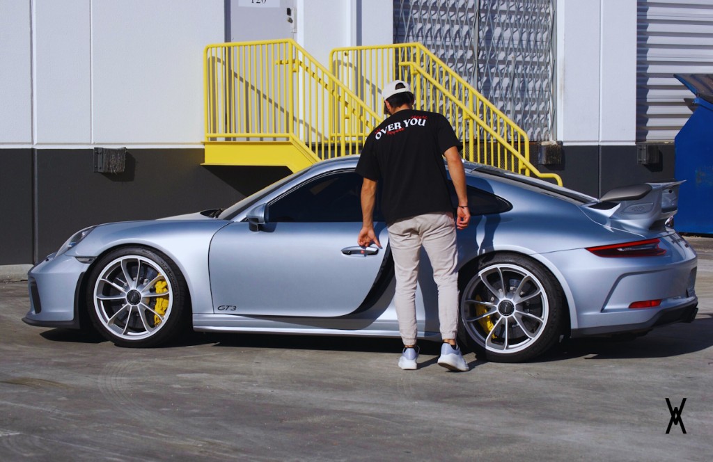 Person wearing Over You shirt next to a Porsche GT3